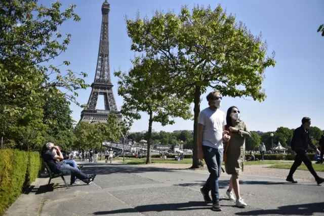 French people wearing masks walk near the Eiffel Tower in Paris