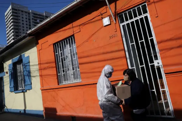 A woman receives a food parcel as part of a government distribution programme in Santiago, Chile, on 22 May 2020