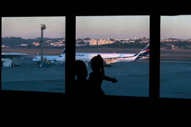 A Colombian citizen and a girl look at planes sitting at the tarmac of Guarulhos International Airport, in Guarulhos, near Sao Paulo, Brazil, on 26 May 2020.