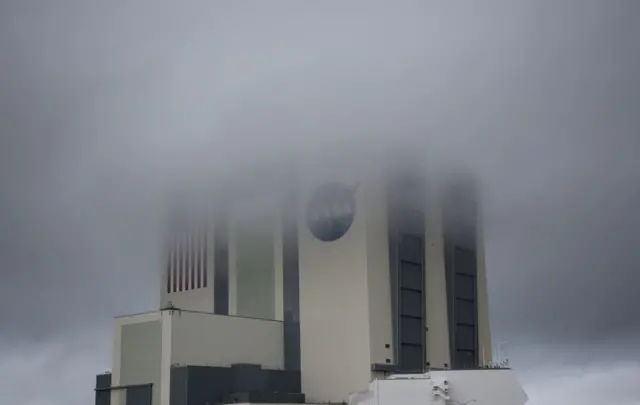 The massive Vehicle Assembly Building is shrouded in fog as stormy weather greeted launch day at the Kennedy Space Center in Florida