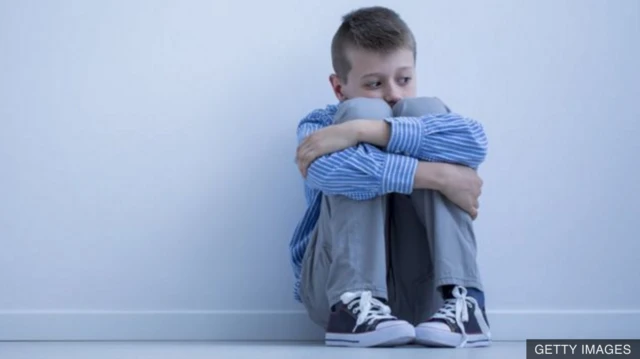 Lone child sitting hugging knees