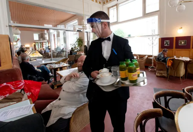 A waiter wears a face shield as he serves customers in Vienna