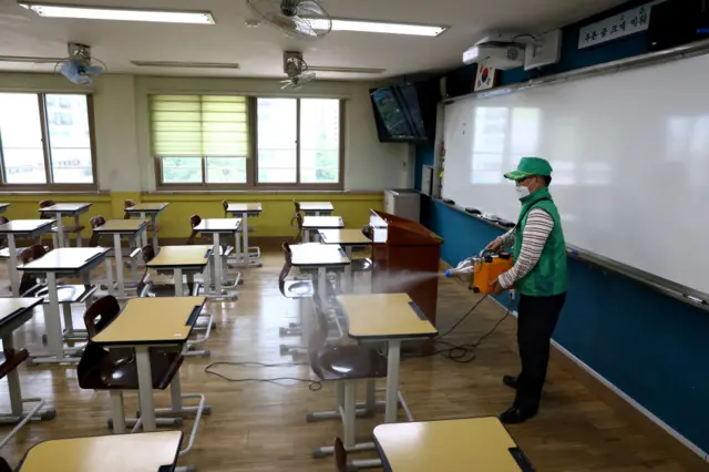 A disinfection worker sprays anti-septic solution at a classroom in Seoul