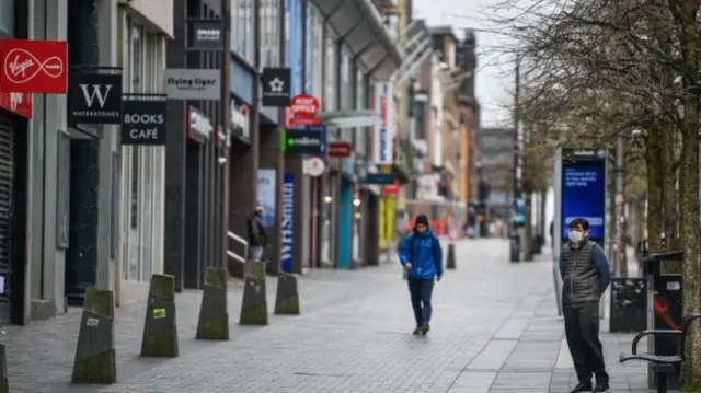 A pedestrian walks past some closed shops