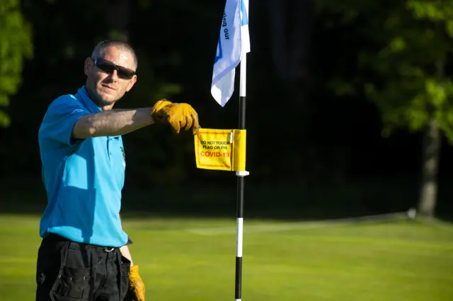 A member of Bruntsfield Links Golf Club shows a Covid-19 warning sign