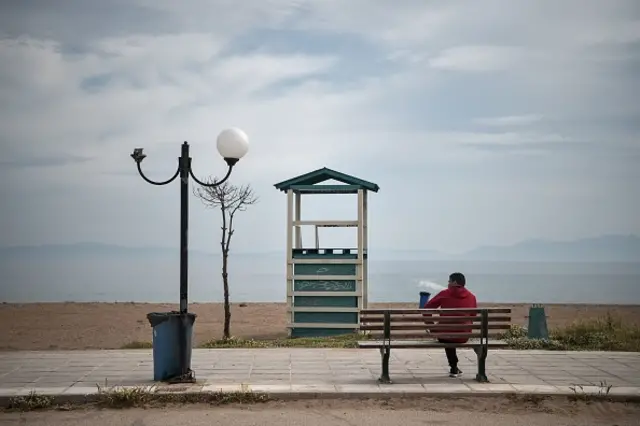 A man sits by an empty beach in the port town of Rafina near Athens