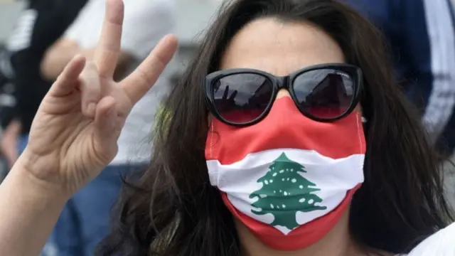 A protester in Tripoli, Lebanon, wears a face mask made with a flag of Lebanon (3 May 2020)