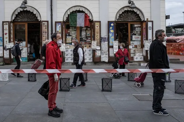 People wait in line at a safe distance to shop at a food market of Porta Palazzo in Turin, Italy