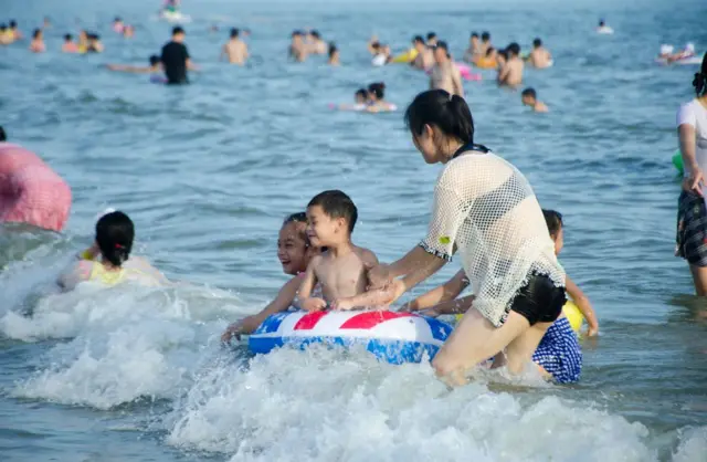 People play in the sea at Silver Beach tourist resort on the third day of 5-day International Workers' Day holiday