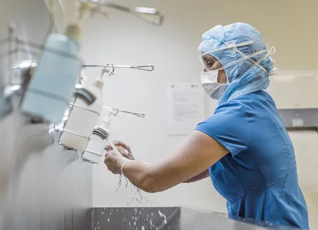 nurse in ppe washing hands