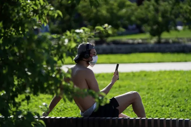 A man wearing a face mask sitting in the 'Biblioteca degli alberi' park on May 04, 2020 in Milan