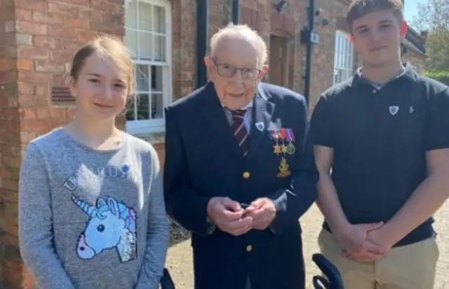 Captain Tom Moore was awarded the badge by his grandchildren Georgia (left) and Benji (right)