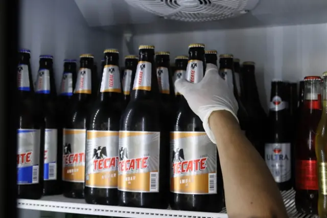 A worker of the Mexican company Grupo Modelo organizes beer bottles for sale in a store in Mexico City, Mexico, 03 April 2020