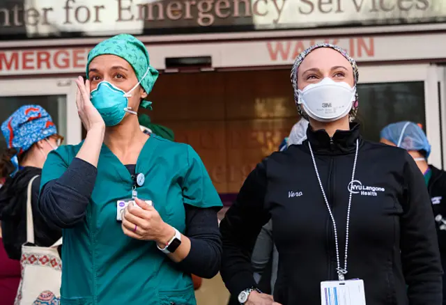 Medical workers stand outside NYU Langone Health hospital as people applaud