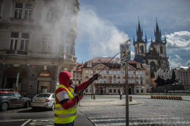 A worker cleans a traffic sign at Old Town Square in Prague, Czech Republic