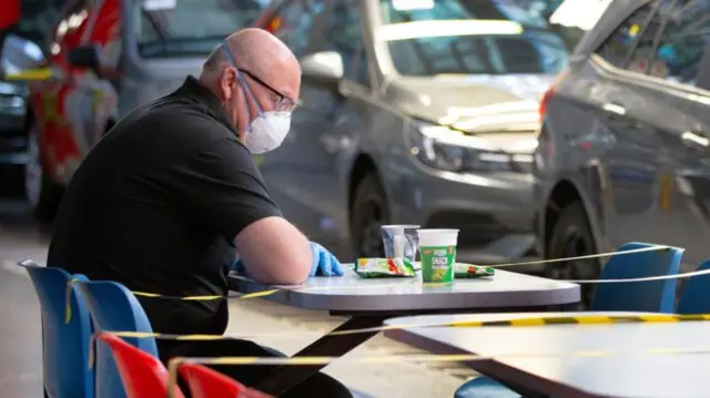 Man wearing a mask at a table