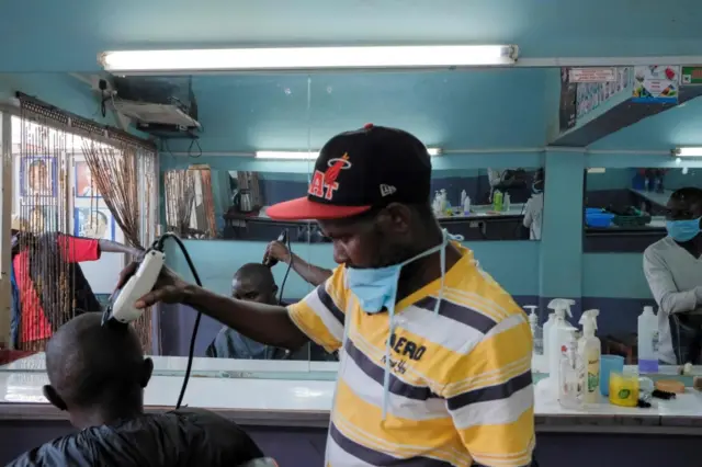 A barber gives a haircut to a customer in Kenya