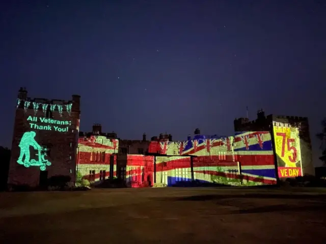 Muncaster Castle illuminated in the colours of the union jack, as well as a VE Day display and a thank you to veterans with an image of Captain Tom Moore