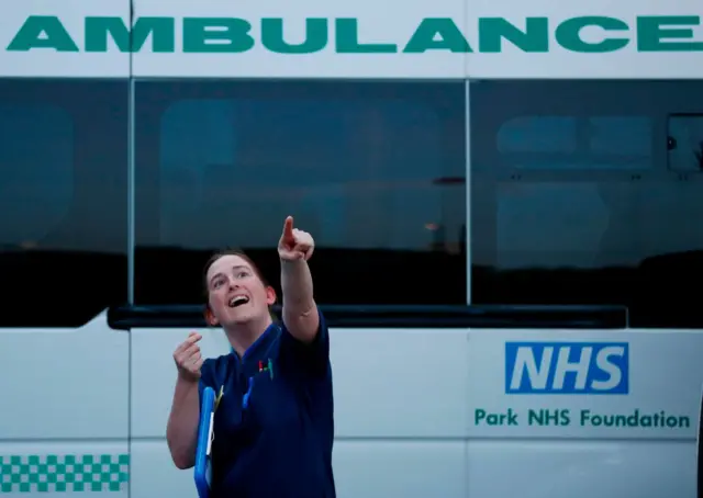 A matron reacts as she spots a drone flying overhead during a national "clap for carers" tribute