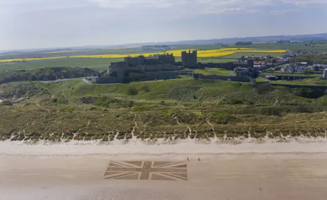 The giant union jack drawn in the sand in front of Bamburgh Castle