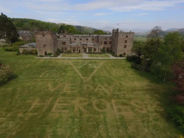 The message "VE Day Heroes" cut into the grass in front of Muncaster Castle