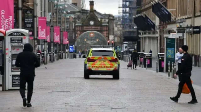 A police car and a few pedestrians in a Glasgow street