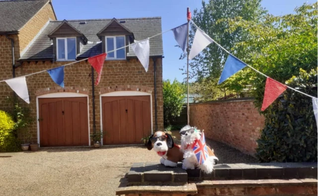 Toy dogs sitting on a wall draped in a Union Jack flag