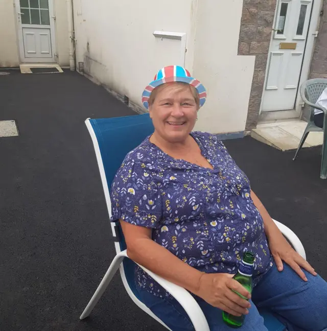 Woman sits with beer in hand and union jack flag hat on