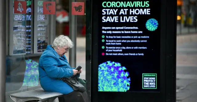 woman waits at a bus stop in Edinburgh