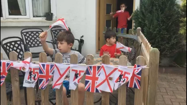 Children fly Jersey flags in garden