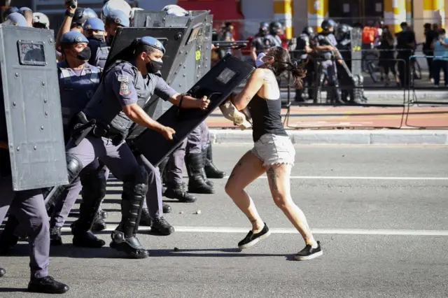 A person is hit with a shield by police during Brazilian President Jair Bolsonaro protests in Sao Pablo