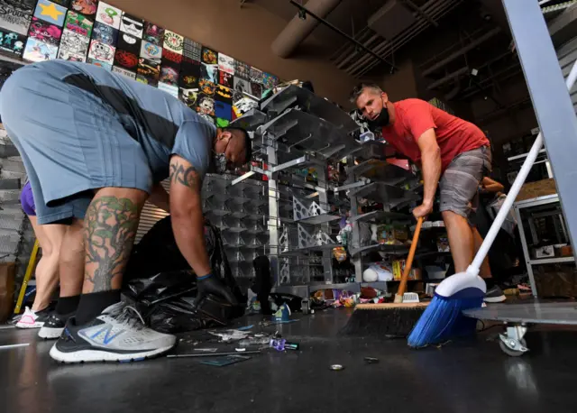 A volunteer in Long Beach, California, helps a shopkeeper clean up a Hot Topics clothing store