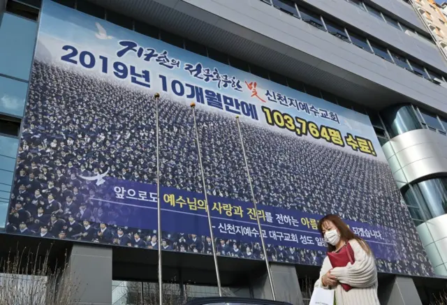 A woman wearing a face mask walks in front of the Daegu branch of the Shincheonji Church