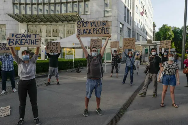 Protesters hold up signs during a demonstration in front of the US consulate, in Milan, Italy, 28 May 2020,