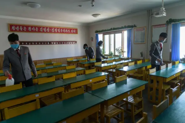 Students wearing face masks disinfect a classroom prior to a lecture