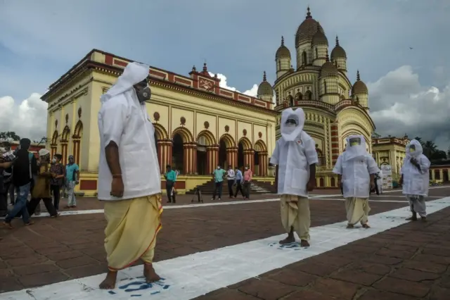 Hindu priests stand on a white line keeping a distance