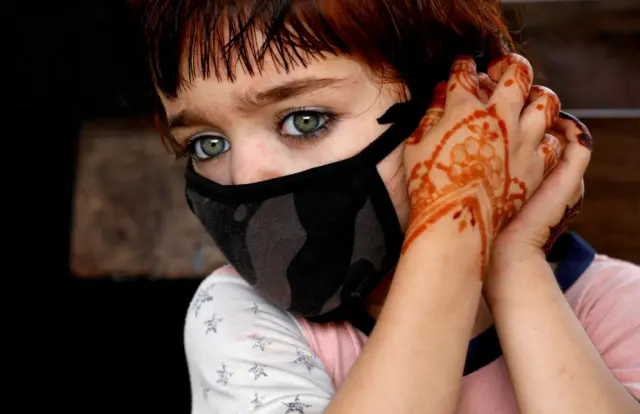 4-year-old Tasmina adjusts her protective face mask as she waits with her family for a train at a railway station, as the outbreak of the coronavirus disease (COVID-19) continues, in Karachi, Pakistan June 9, 2020