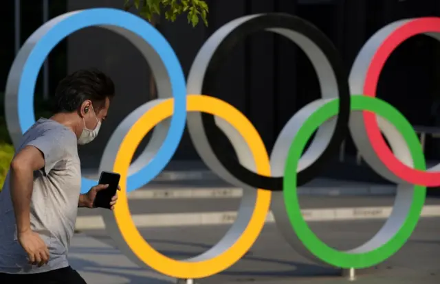 A man runs past the Olympic rings monument outside the Japan Olympic Museum in Tokyo