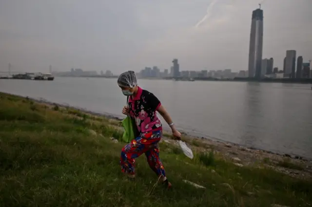 A woman wears a face mask on the banks of the Yangtze River in Wuhan