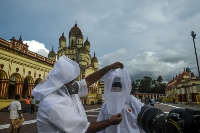 Hindu priests help each other with protective head gear