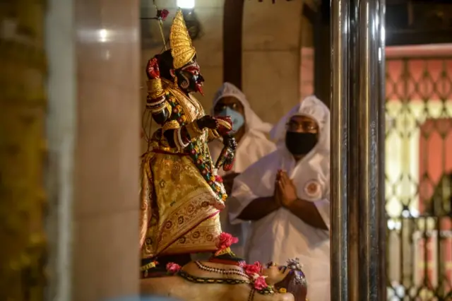 Priests perform rituals in front of the idol of Hindu deity Kali