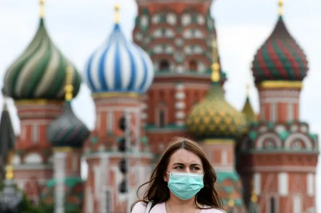 A woman wearing a protective face mask walks in front of the Saint Basil"s Cathedral. 6 June 2020