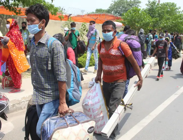 Stranded migrant workers head to a shelter home in Tau Devi Lal Stadium