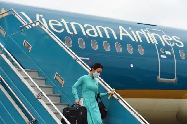 A Vietnam Airlines flight crew member wearing face mask disembarks from a flight at Noi Bai International Airport in Hanoi.