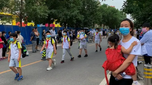 Children and a mother wearing face masks as they leave a school in Beijing