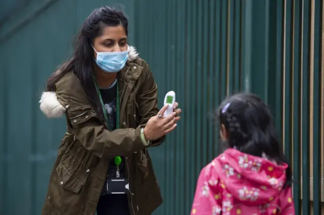 Primary school pupil have her temperature taken