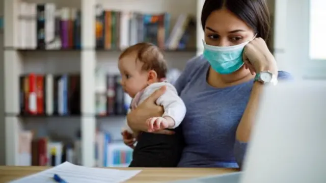 Young woman with baby sits at computer