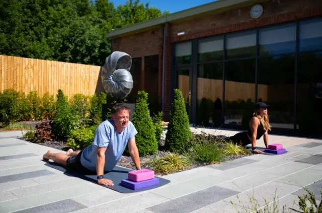 Two people perform yoga outside