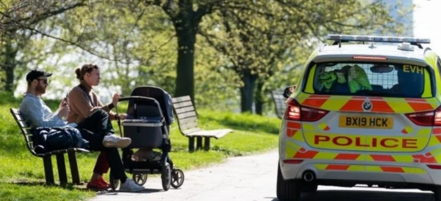 people and a police car in a park