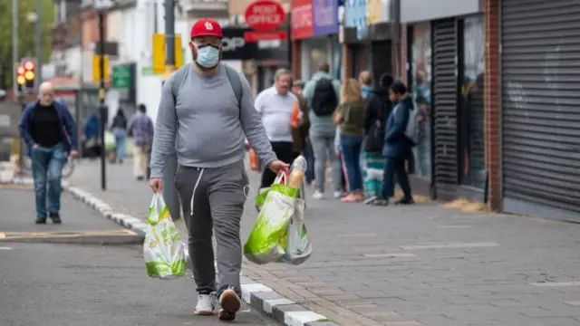 A man walks along a temporarily widened section of pavement to allow social distancing in Kings Heath, Birmingham